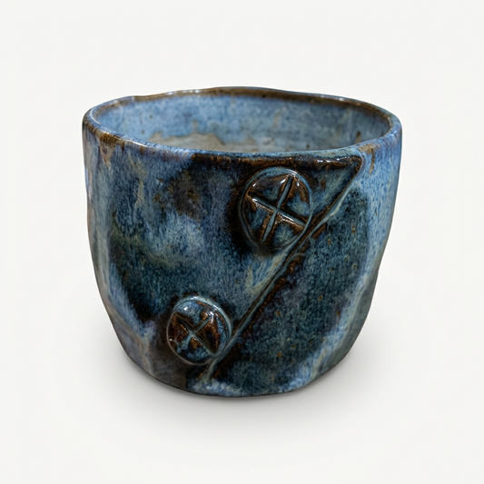 Blue button-decorated vessel on soft white