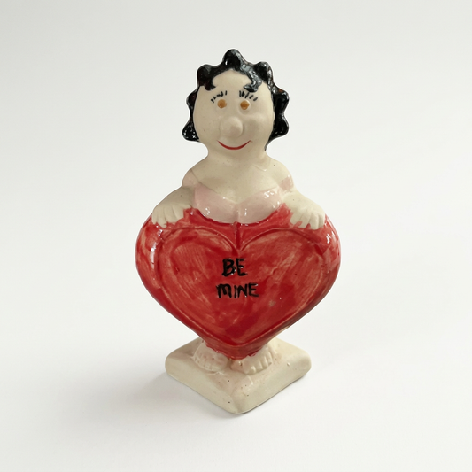 Heart-holding figurine on a soft-white background